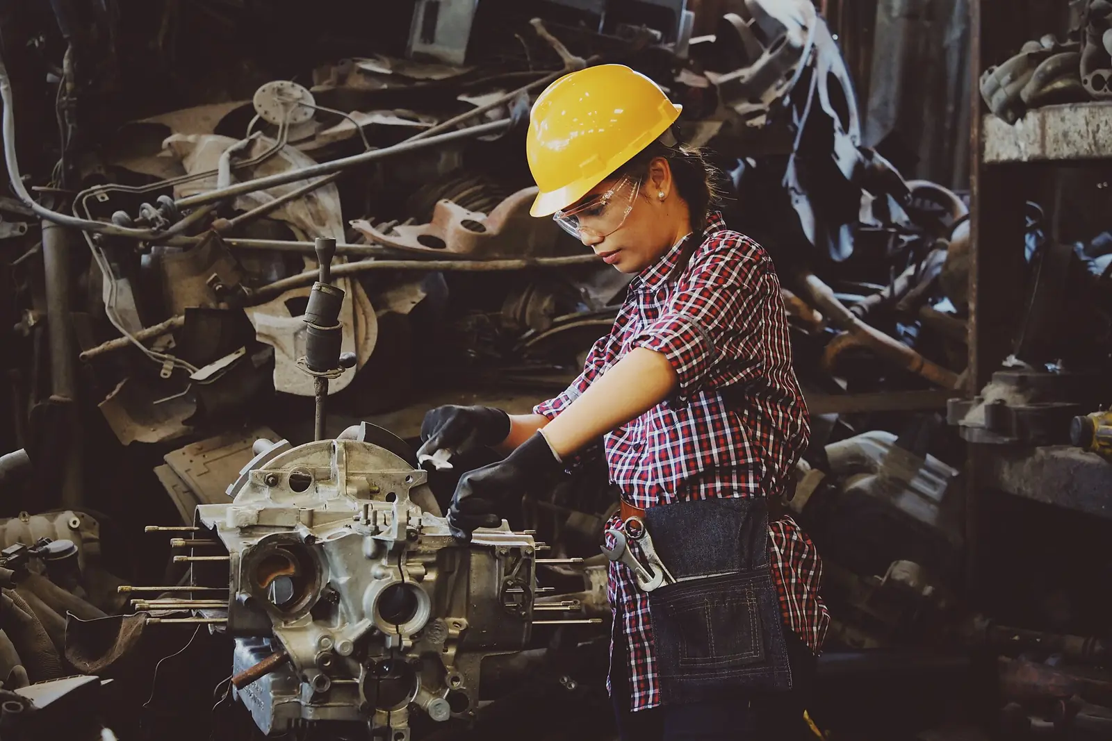 Baretli bir teknisyen motor parçası üzerinde çalışıyor
